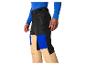 Personne portant un pantalon de ski noir, bleu et beige et un maillot bleu à manches longues.