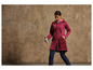 Une femme porte une veste rouge et un pantalon bleu et tient une bouteille d'eau.