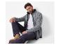 Man in grijs fleecejack, wit T-shirt en donkere jeans.