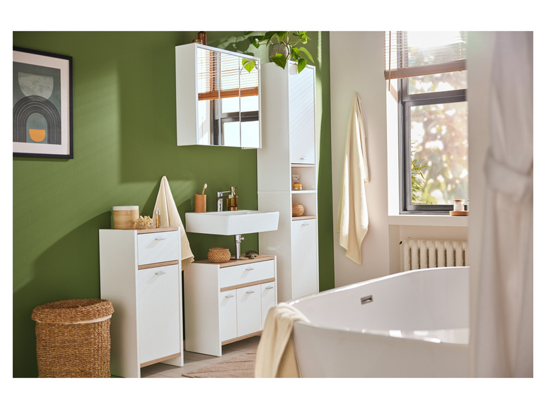 Badkamer met witte wastafel, spiegelkast en bad.