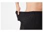 Une personne portant des leggings noirs côtelés, tirant la taille pour montrer l'élasticité.