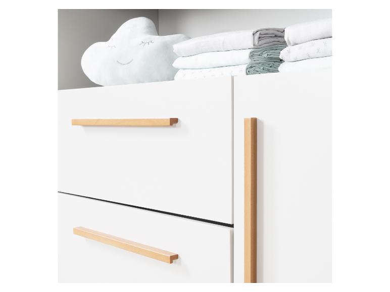 Witte ladekast met houten handgrepen en een wolk-vormig kussen met beddengoed.