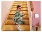 Garçon heureux en pyjama dinosaure assis sur un escalier.