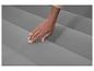 Hand raakt een grijs opblaasbaar matras aan, toont textuur en comfort.