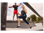 Een man en een vrouw trainen met dumbbells en weerstandsbanden buiten.
