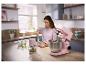 Femme dans la cuisine préparant un repas avec un robot pâtissier rose et un hachoir.