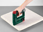 Une agrafeuse Parkside verte est utilisée pour fixer le tissu à une chaise.