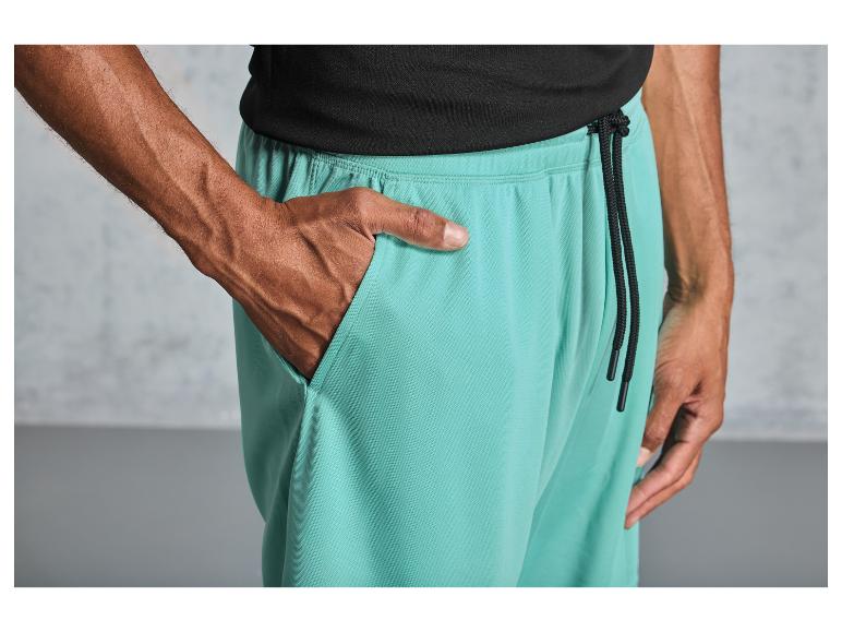 Un homme porte un pantalon de survêtement turquoise avec un cordon noir.