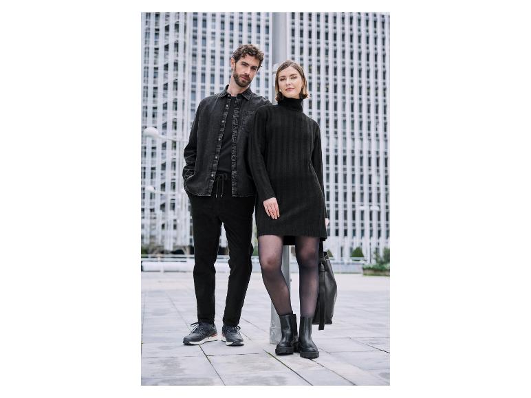 Koppel in stijlvolle zwarte kleding op achtergrond van moderne gebouwen.