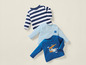 Trois t-shirts pour bébé: un à rayures, un bleu clair avec une maison et un bleu foncé avec un avion.