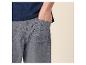 Homme en t-shirt bleu et short gris, main dans la poche.
