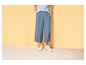Een vrouw draagt blauwe, gebloemde broek met witte sneakers.