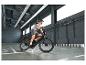 Homme en casque et gilet roulant à vélo électrique noir dans un hall.