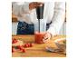 Femme mixant de la soupe de tomates avec un mixeur plongeant, avec des tomates fraîches et du sel.