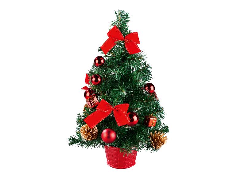 Een kleine groene kerstboom versierd met rode ballen, strikken en dennenappels.