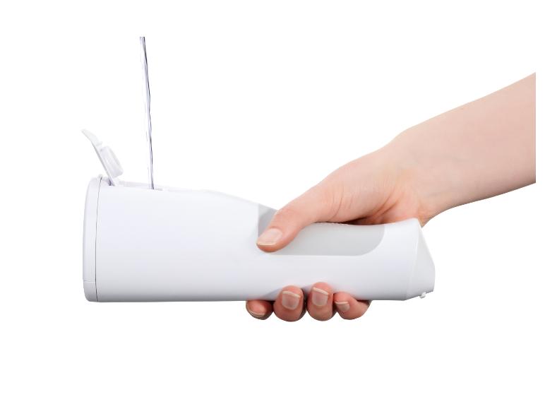 Hand houdt een witte monddouche vast die met water wordt gevuld.