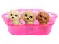 Drie speelgoedpuppy's in verschillende kleuren, geplaatst in een roze pootvormige houder.