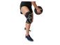 Persoon in zwarte sportshorts, kniebrace en sneakers, met een medicijnbal.