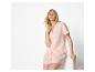 Vrouw in perzikkleurige pyjama met overhemd met korte mouwen en korte broek.