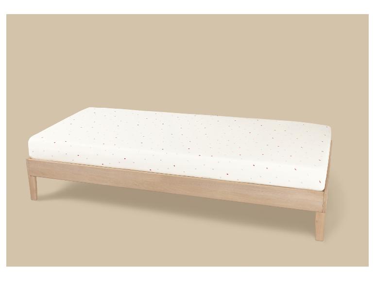 Houten commode met een wit matras met kleurrijke stippen.