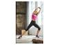 Femme en débardeur de sport rose et leggings noirs faisant des étirements.
