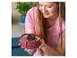 Een vrouw houdt een ronde, roze bakvorm vast met een dessert van Oreo-koekjes en gojibessen.