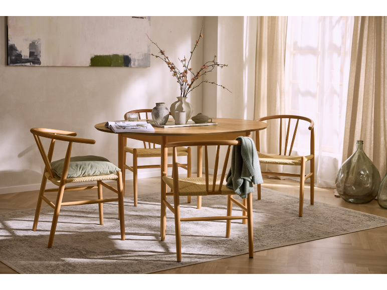 Table à manger en bois avec quatre chaises, décorée de vases et de fleurs, sur un tapis.