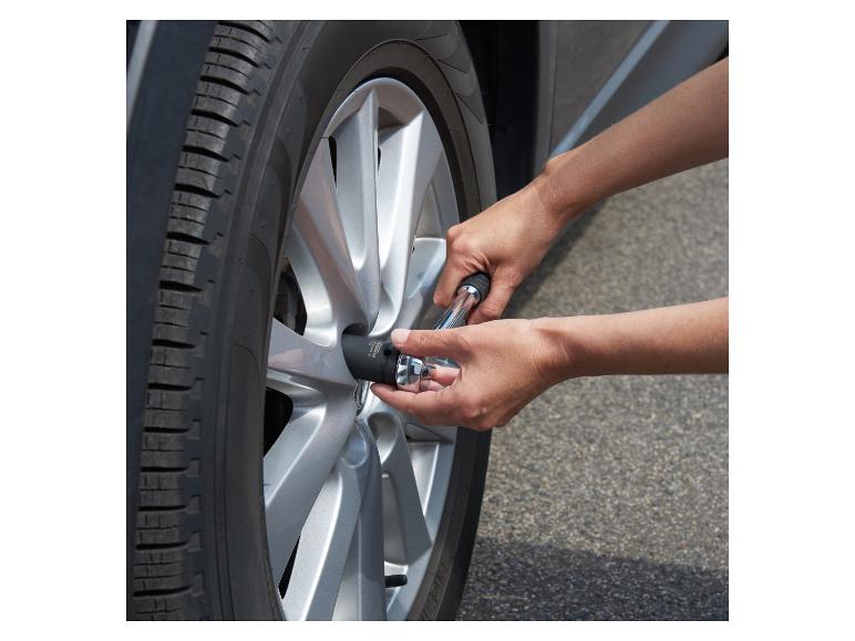 Mains utilisant une clé à douille pour serrer l'écrou de roue d'une voiture.