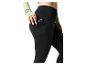 Femme en legging noir avec un téléphone dans la poche latérale et un haut vert clair