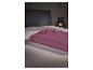 Opgevouwen paars hoeslaken op een bed met grijs hoofdbord en decoratieve lamp.
