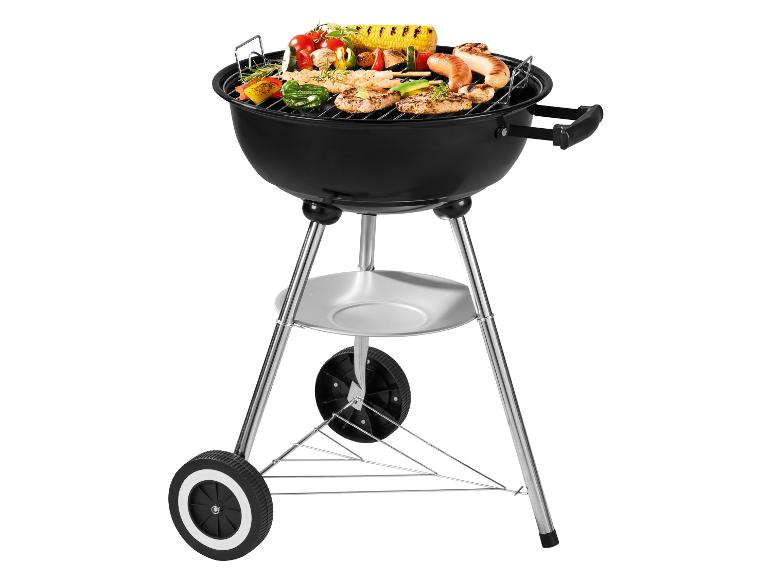 Zwarte houtskoolbarbecue op wielen, gevuld met gegrild vlees en groenten.