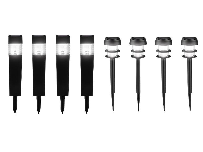 Huit lampes solaires de jardin noires, quatre carrées et quatre rondes.