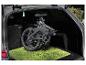 Vélo électrique pliant dans le coffre d'une voiture sur un tapis vert.