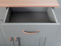 Een open lade met koperen handgreep van een grijs dressoir.