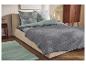 Bed met grijze sprei, kussens met bladpatroon en houten nachtkastje.