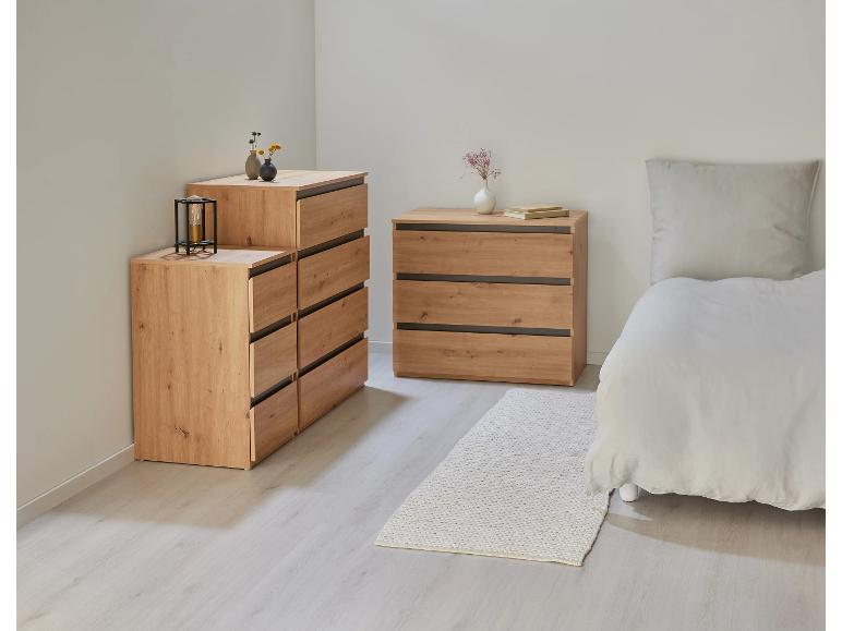 Deux commodes en bois et un lit avec des draps blancs dans une pièce claire.