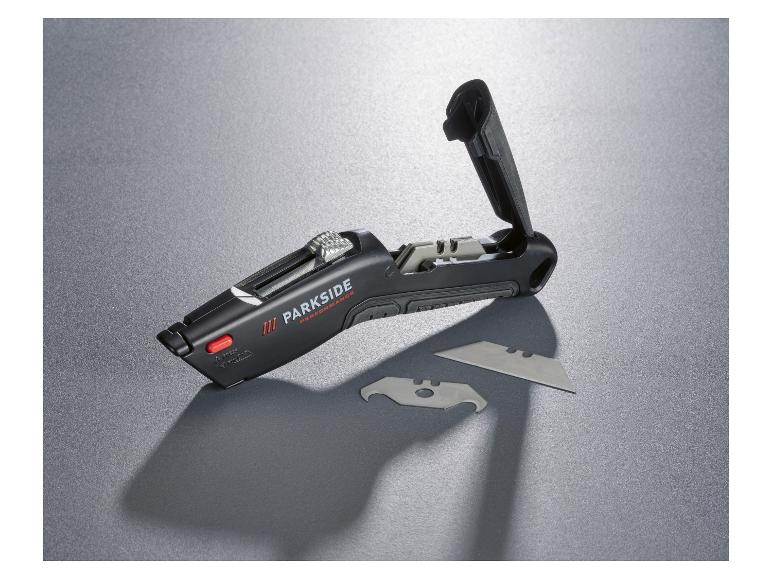 Cutter noir ouvert avec lames de rechange sur une surface grise.