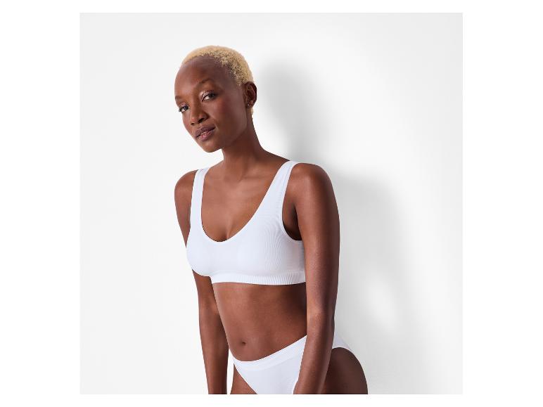 Femme aux cheveux blonds en soutien-gorge de sport et culotte blancs sans couture.