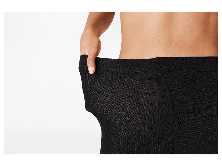 Une personne tire sur la taille d'un legging noir pour montrer qu'il est trop grand.