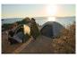 Deux personnes campent au bord de la mer avec deux tentes Crivit et un matelas de couchage au coucher du soleil.