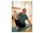 Vrouw in groen T-shirt en zwarte legging rekt zich uit op een yogamat.