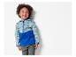 Een lachende peuter modelleert een turquoise en blauw softshell jack met een reisthema.