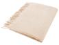Beige deken met franjes, opgevouwen op een witte achtergrond