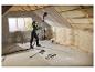 Vrouw schuurt het plafond met de PARKSIDE wandschuurmachine op een zolder in renovatie.