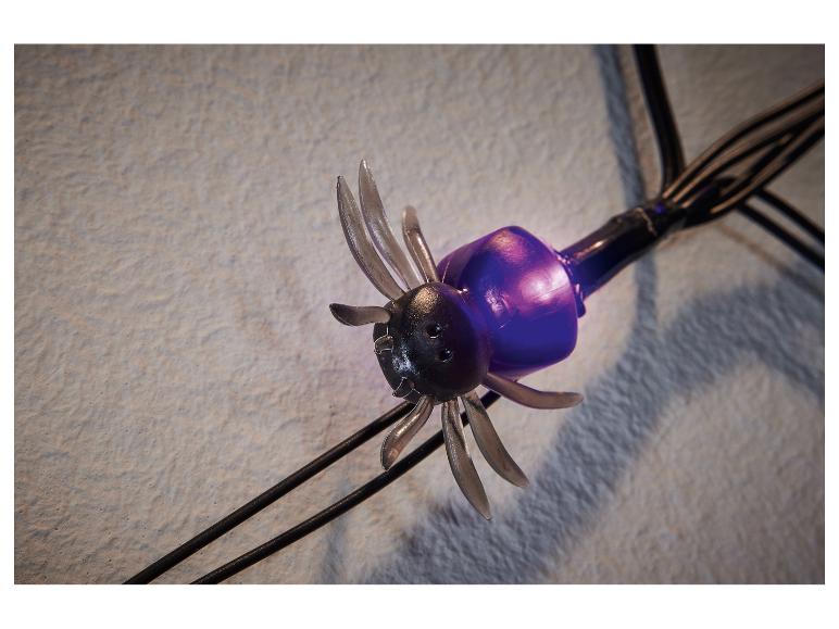 Een decoratieve spinvormige lamp met een paarse behuizing en zwarte poten.