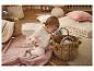 Baby in wit rompertje speelt met rieten mand in gezellige kamer.