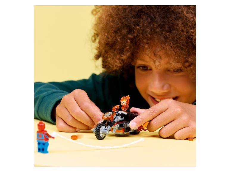 Kind speelt met speelgoedmotor en figuren op een gele achtergrond.