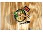 Kom ramen met kip, tofu, champignons en paksoi op een bamboemat.