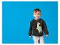 Garçon souriant en sweat-shirt noir dinosaure et pantalon de jogging gris.