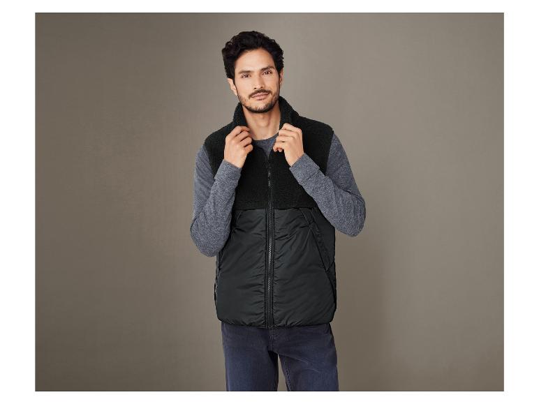 Man draagt een zwarte fleece-vest met een capuchon.